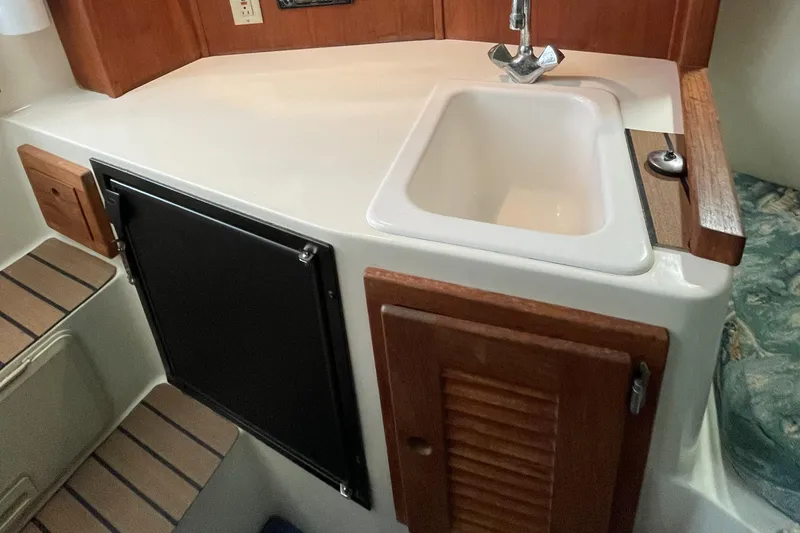 Slide: The Image of 2004 Carolina Classic 28 boat interior with sink and wooden cabinetry. - 28