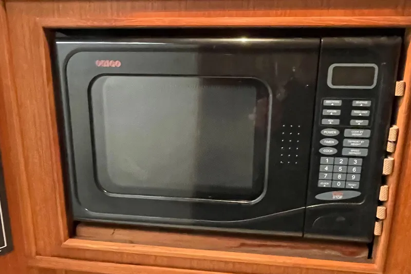 Slide: The Image of Built-in black microwave in a 2004 Carolina Classic 28 boat kitchen. - 30