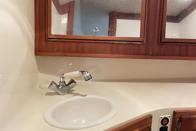 Slide: The Image of Bathroom sink area in a 2004 Carolina Classic 28 boat, featuring wooden cabinetry. - 32