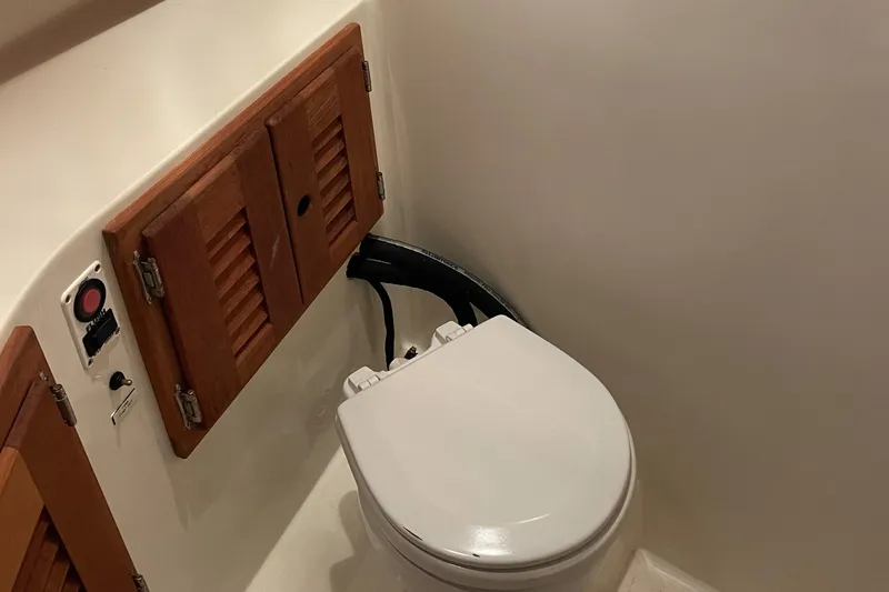 Slide: The Image of 2004 Carolina Classic 28 boat bathroom with wooden cabinets and a white toilet. - 34