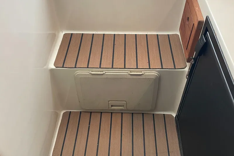 Slide: The Image of 2004 Carolina Classic 28 boat interior steps with striped mats and storage compartment. - 38