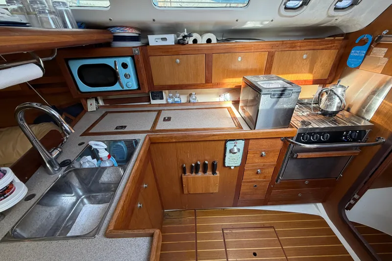 Slide: The Image of 1999 Hunter 380 yacht kitchen with wooden cabinetry, sink, stove, and microwave. - 21