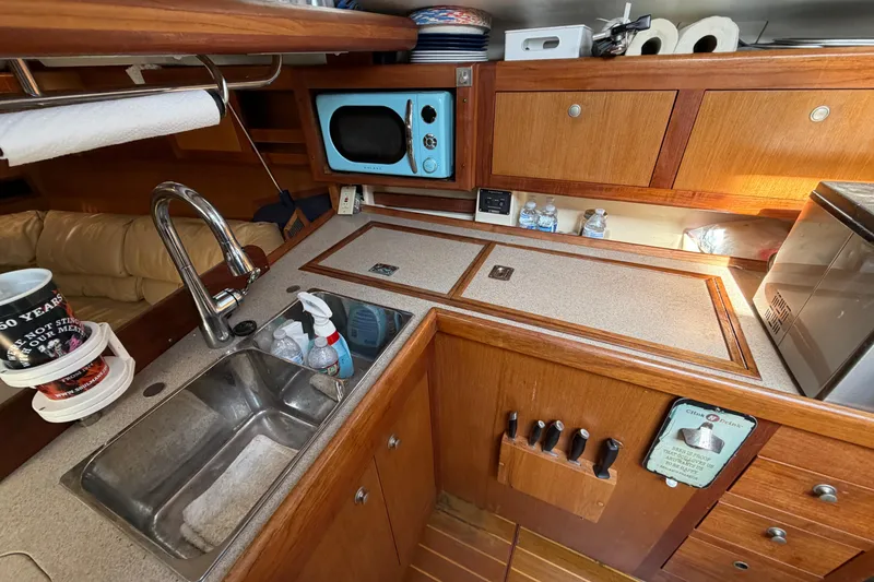 Slide: The Image of 1999 Hunter 380 yacht kitchen with wooden cabinets, sink, and microwave. - 22