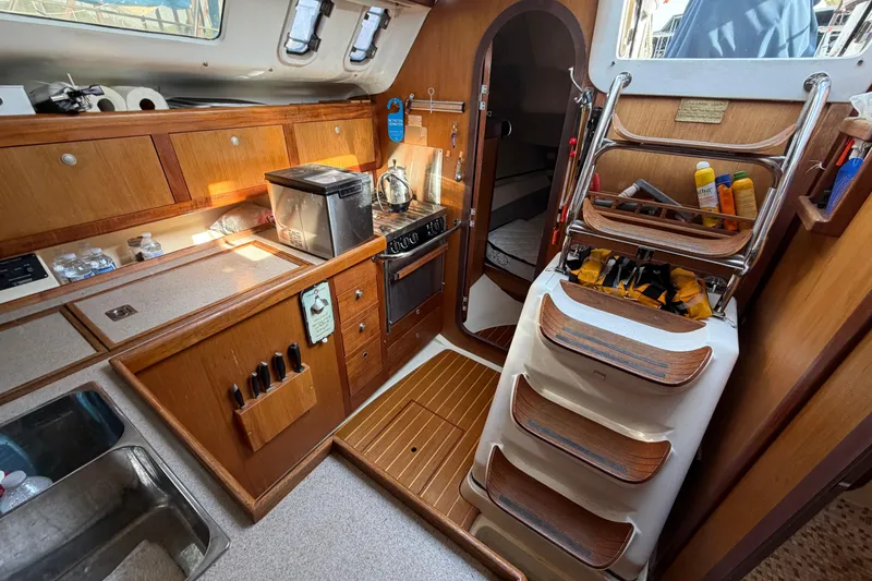Slide: The Image of Interior of a 1999 Hunter 380 sailboat, featuring a compact kitchen and wooden cabinetry. - 24