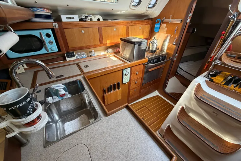 Slide: The Image of 1999 Hunter 380 yacht kitchen with wooden cabinetry, sink, and appliances. - 25
