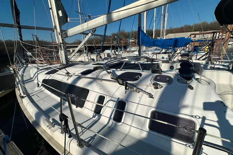 Slide: The Image of 1999 Hunter 380 sailboat docked, showcasing deck and rigging under clear blue sky. - 3