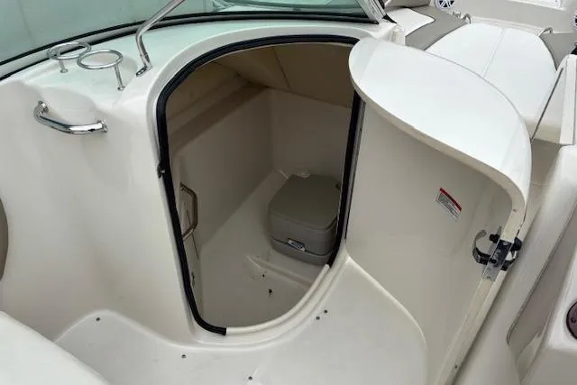 Slide: The Image of 2007 Sea Ray 240 Sundeck boat interior with open cabin door and compact toilet. - 14