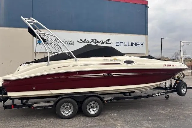 Slide: The Image of 2007 Sea Ray 240 Sundeck boat on trailer, maroon and white, parked outdoors. - 2