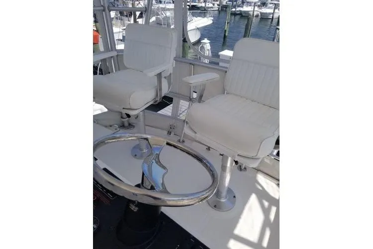 Slide: The Image of 2005 Luhrs 41 Convertible boat helm with white captain chairs and steering wheel. - 29