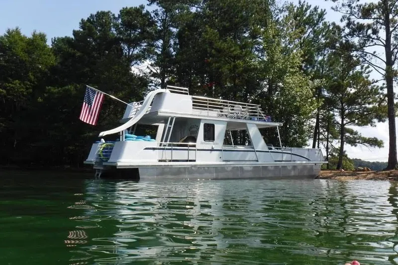 Slide: The Image of 2008 Destination Yachts 45X14 houseboat on a serene lake, surrounded by trees. - 24