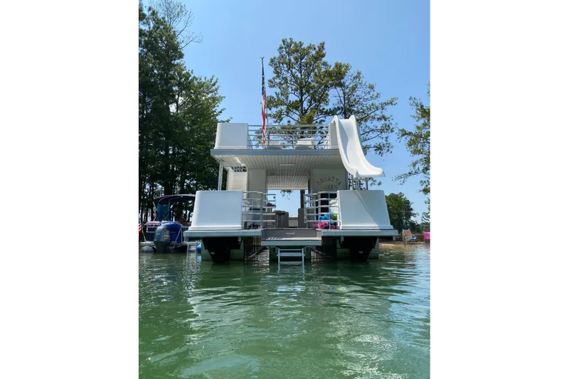 Slide: The Image of 2008 Destination Yachts 45X14 houseboat with slide, docked on a serene lake. - 26