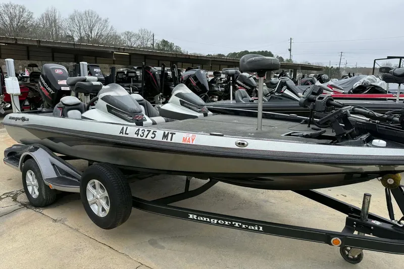Slide: The Image of 2015 Ranger Z118 Comanche boat on trailer, parked outdoors with other boats. - 2