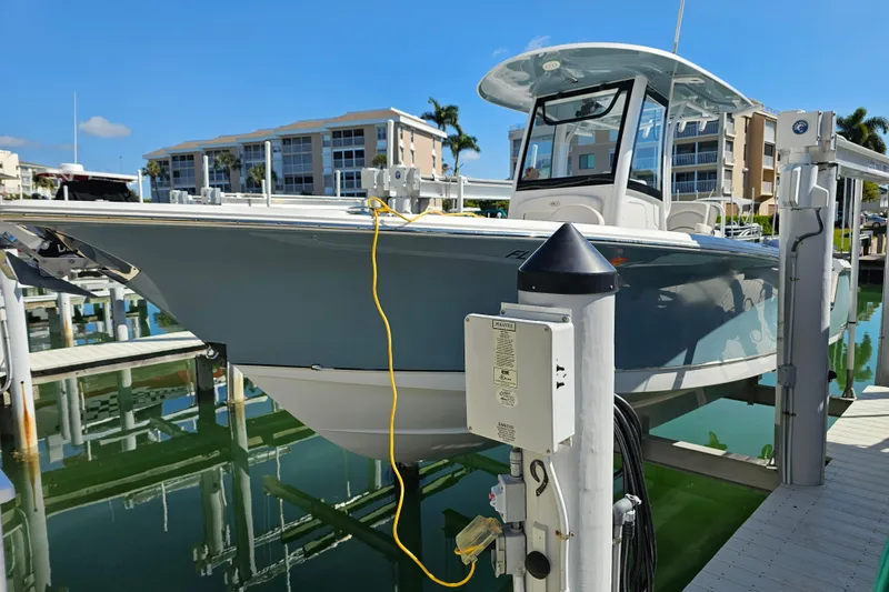 Slide: The Image of 2021 Sea Hunt Gamefish 27 boat docked at marina with modern buildings in background. - 8