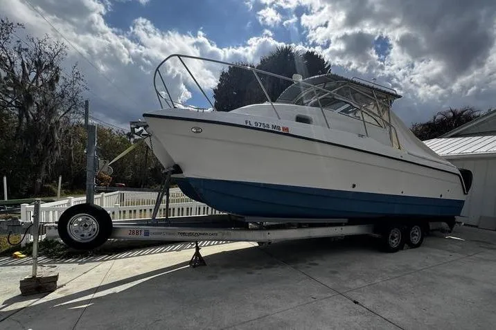 The Image of 2001 Glacier Bay 260 Canyon Runner boat on trailer, parked outdoors under cloudy sky. - 0