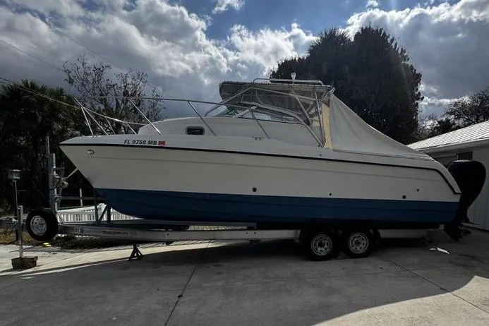 Slide: The Image of 2001 Glacier Bay 260 Canyon Runner boat on trailer, parked outdoors under cloudy sky. - 8