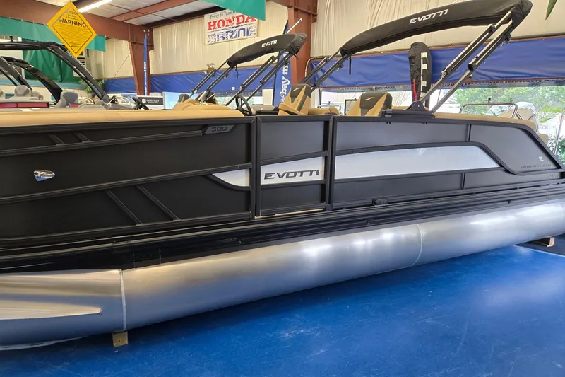 Slide: The Image of 2026 Evotti 521QL pontoon boat displayed indoors with sleek black and silver design. - 2