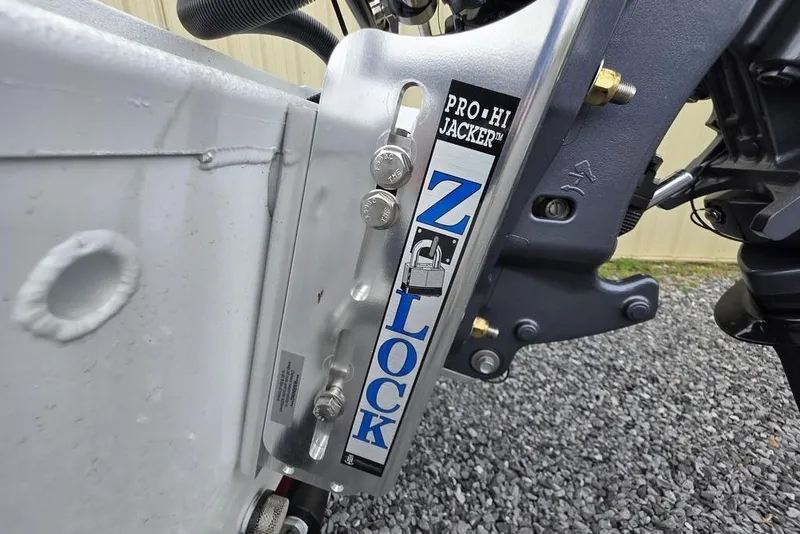 Slide: The Image of 2026 Xpress H20CC boat with Pro Hi Jacker Z-Lock system on gravel surface. - 5