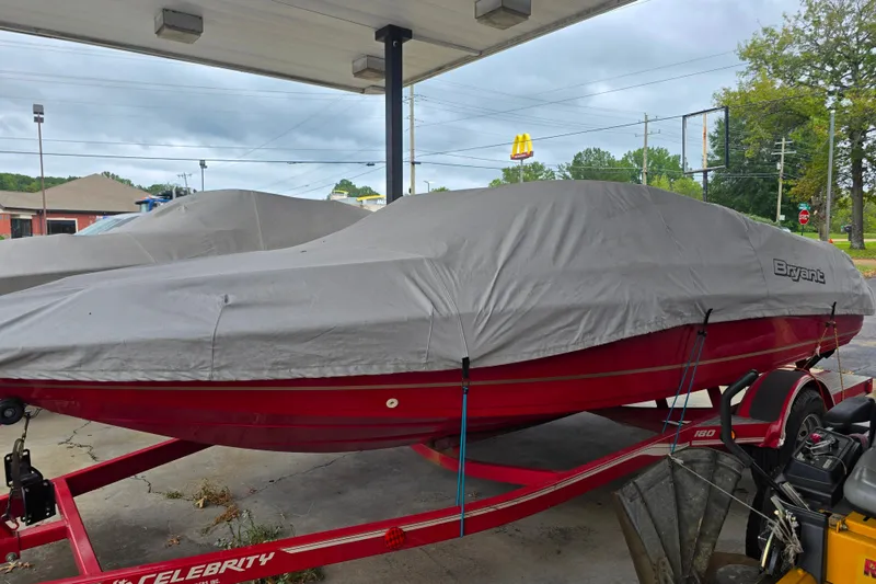 Slide: The Image of Covered 1995 Bryant 189 Limited boat on red trailer at a parking area. - 1