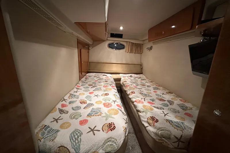 Slide: The Image of 2004 Regal Commodore 3860 cabin with twin beds and nautical-themed bedding. - 24