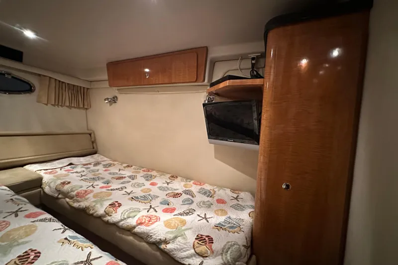 Slide: The Image of 2004 Regal Commodore 3860 cabin with twin beds, wood cabinetry, and mounted TV. - 25