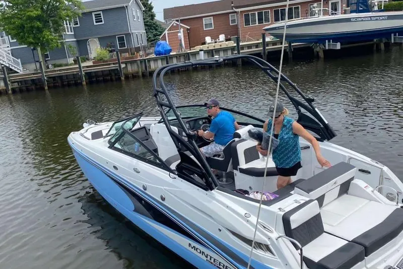 Slide: The Image of 2021 Monterey Boats M65 on a calm residential waterway, featuring sleek design and modern amenities. - 4