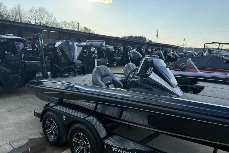 Slide: The Image of 2024 Triton 20XP Patriot boat on trailer, parked outdoors, surrounded by other boats. - 13