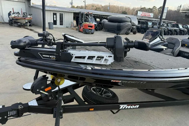 Slide: The Image of 2024 Triton 20XP Patriot boat with Minn Kota trolling motor, parked outdoors. - 15