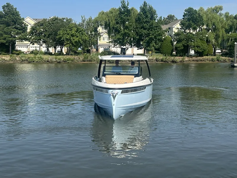 Slide: The Image of A 2027 Saxdor 320 GTO cruising on a calm river, surrounded by trees and houses. - 6