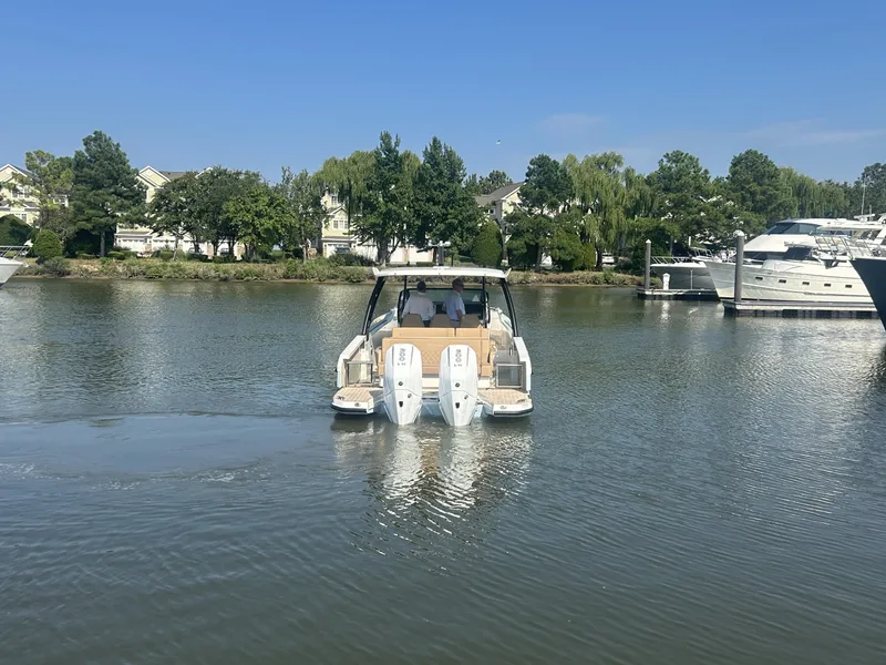 Slide: The Image of A 2027 Saxdor 320 GTO cruising on a calm river, surrounded by trees and other boats. - 2