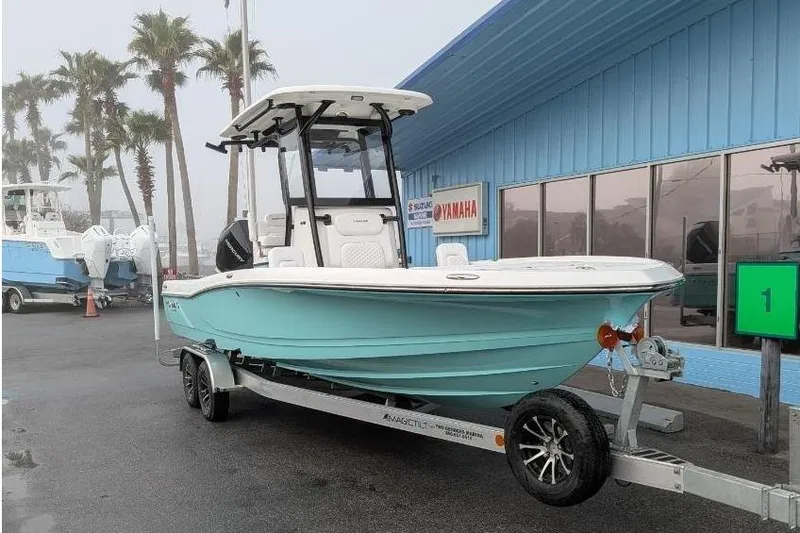 Slide: The Image of 2026 Caymas 26 HB boat on trailer in front of blue building. - 2