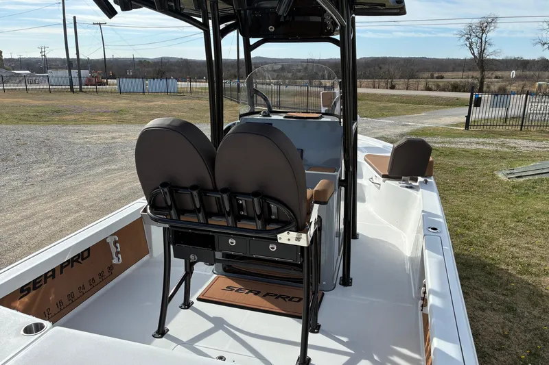 Slide: The Image of 2026 Sea Pro 250 Bay boat interior with dual seats and console, parked outdoors. - 3
