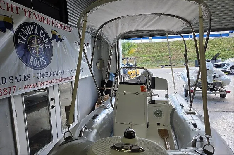 Slide: The Image of 2015 AB Inflatables Oceanus 12 VST with Evinrude 40HP in showroom, featuring canopy and banner. - 2