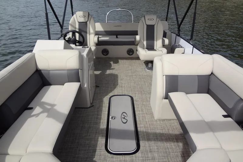 Slide: The Image of 2022 Harris FloteBote 230 Cruiser interior with plush seating on a calm lake. - 14
