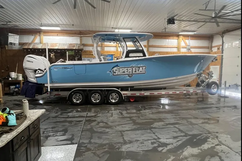 The Image of 2022 Sportsman Open 322 Center Console boat in a garage on a trailer. - 0