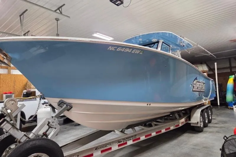 Slide: The Image of 2022 Sportsman Open 322 Center Console boat on trailer in indoor storage. - 2