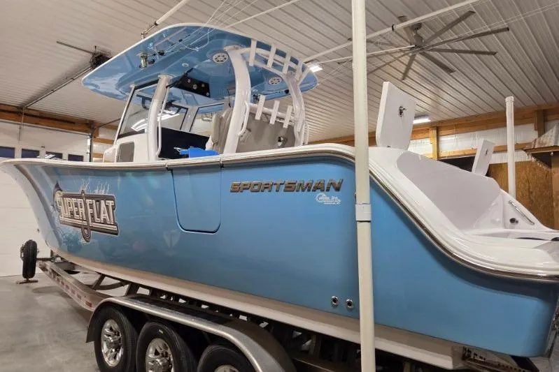 Slide: The Image of 2022 Sportsman Open 322 Center Console boat in a garage, blue exterior, on a trailer. - 3