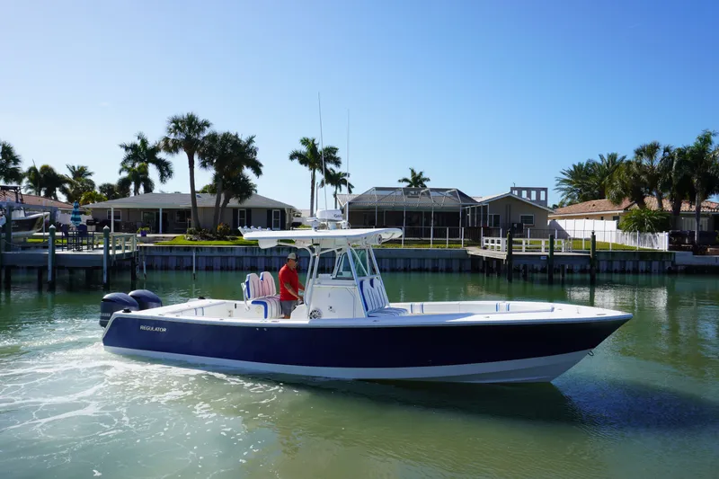 Slide: The Image of 2005 Regulator 32 boat on calm water near coastal homes. - 23