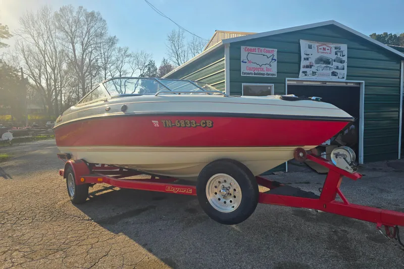 Slide: The Image of Red and white 1997 Bryant 182 boat on trailer, parked outside a green garage. - 11