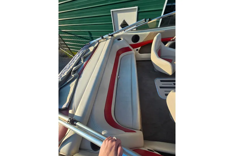 Slide: The Image of 1997 Bryant 182 boat interior with red and white seating, near green building. - 4