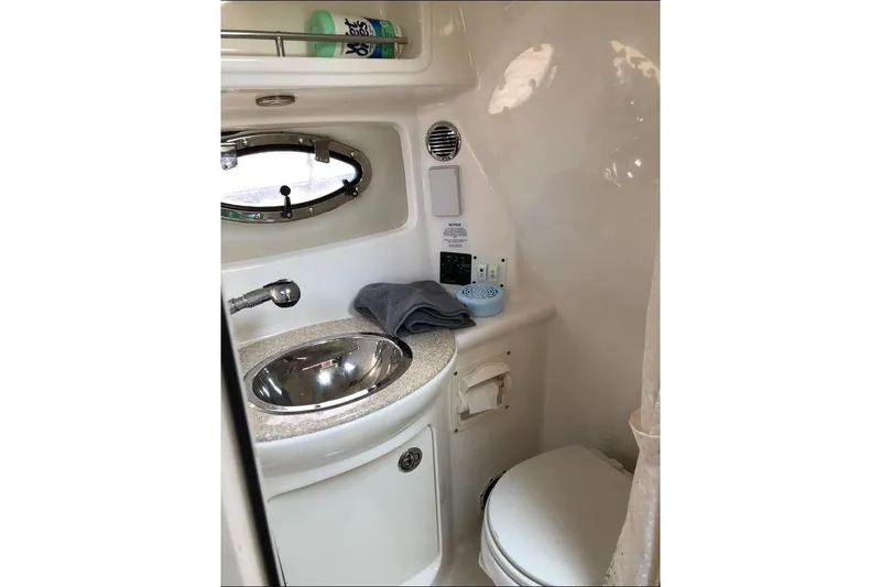 Slide: The Image of 2008 Chaparral Signature 270 boat bathroom with sink, toilet, and porthole window. - 9