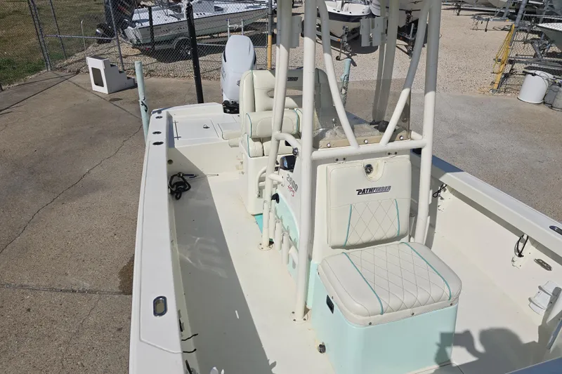 Slide: The Image of 2016 Pathfinder 2600 HPS boat interior with seating and console, parked outdoors. - 19