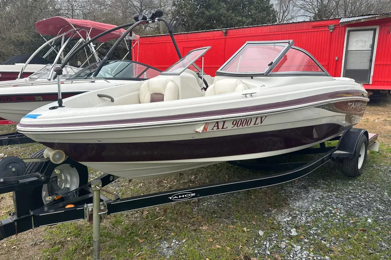 Slide: The Image of 2005 Tahoe Q4 Sport boat on trailer, parked outdoors near red building. - 14