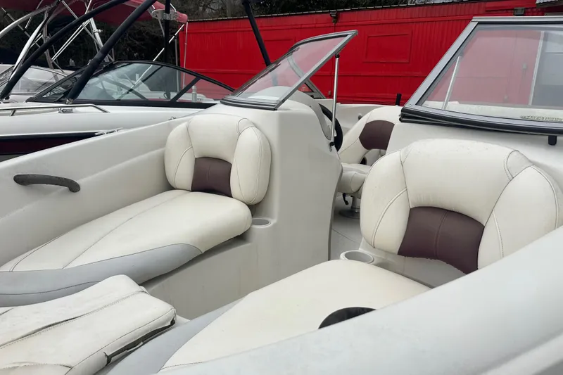 Slide: The Image of 2005 Tahoe Q4 Sport boat interior with white and brown seating, windshield, and cup holders. - 15