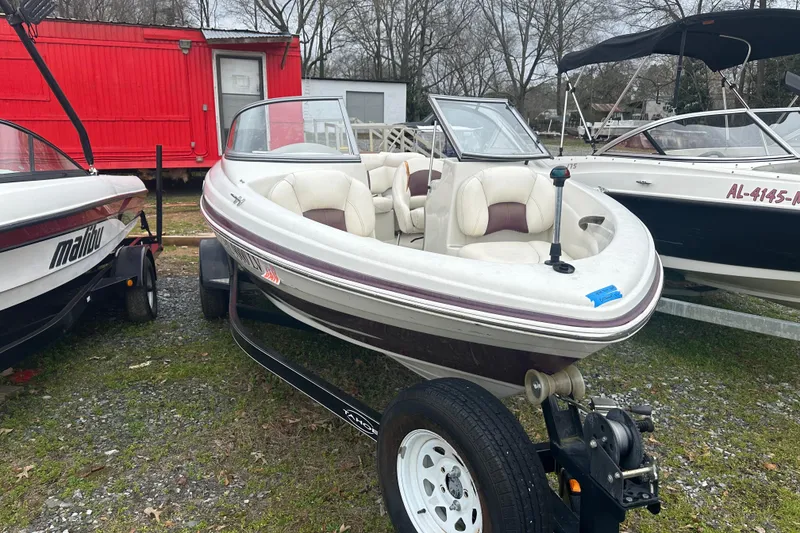 Slide: The Image of 2005 Tahoe Q4 Sport boat on trailer, parked outdoors near other boats. - 4