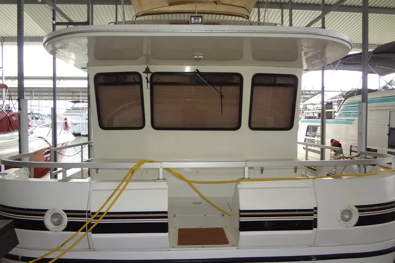 Slide: The Image of Gibson 44 houseboat, 2005 model, docked in a marina with visible windows and railing. - 2