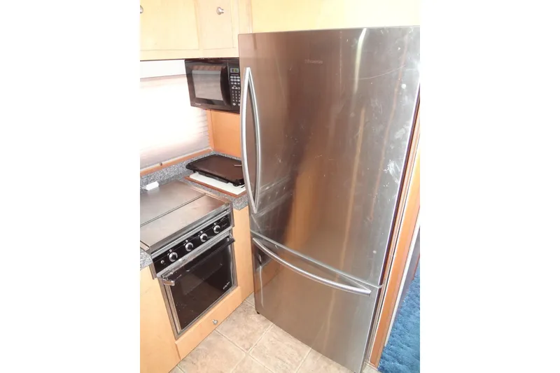 Slide: The Image of Compact kitchen with stainless steel fridge, oven, and microwave in a 2005 Gibson model 44. - 34