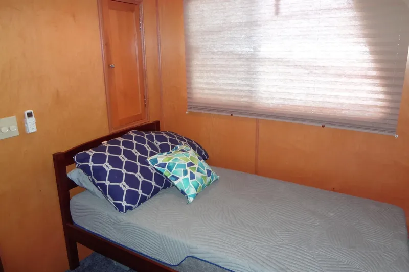 Slide: The Image of Small bedroom with single bed, colorful pillows, and wooden walls in a 2005 Gibson 44. - 37