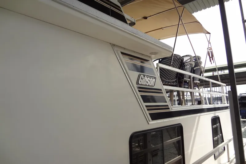 Slide: The Image of 2005 Gibson 44 boat with upper deck seating and canopy in marina. - 4