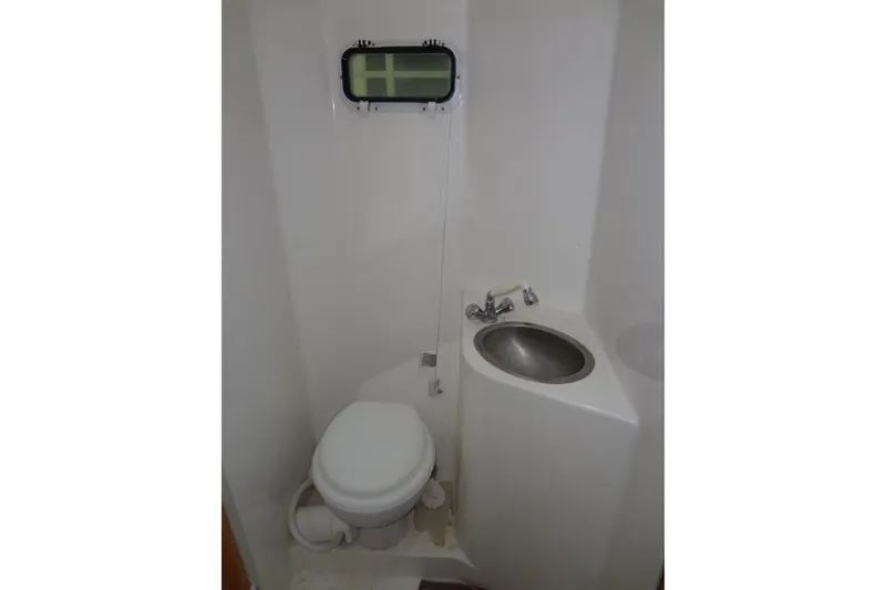 Slide: The Image of Compact bathroom in a 2005 Gibson 44 boat, featuring a toilet, sink, and small window. - 43