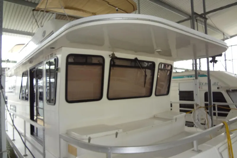 Slide: The Image of 2005 Gibson 44 houseboat in a covered marina, featuring large windows and a spacious deck. - 5